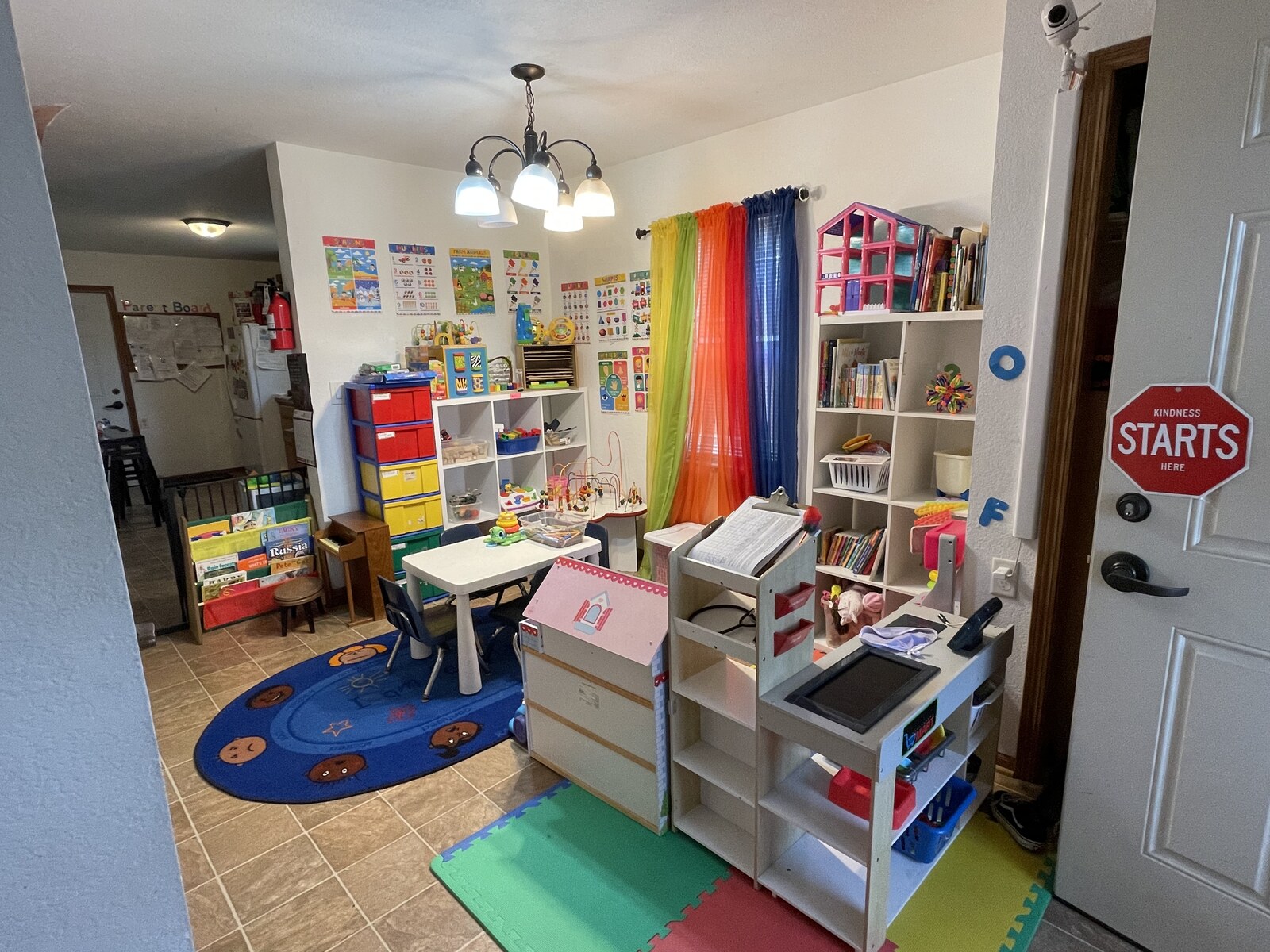 Bright playroom with learning charts, book shelves, toy bins, and a kids' table